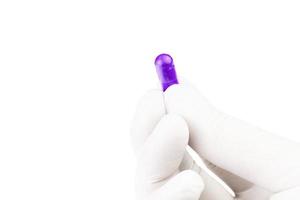 mão na luva médica segurando cápsula de medicamento orgânico de próton cor roxa isolada em fundo branco closeup foto