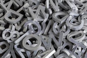 pilha de caracteres do alfabeto de metal branco cortados por máquina de jato de água foto