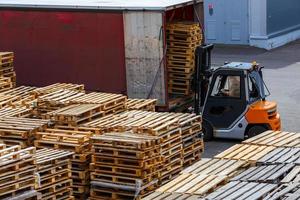 empilhadeira carregando pilhas de paletes de madeira usadas no caminhão - vista em perspectiva de cima foto