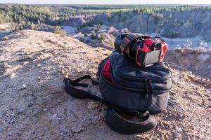 câmera profissional e mochila fotográfica no topo da colina durante o dia de verão foto