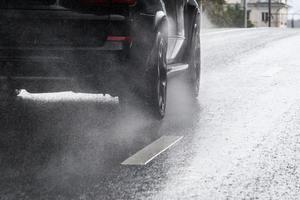 fluxo de respingos de água da chuva das rodas do carro preto em movimento rápido na cidade à luz do dia com foco seletivo foto