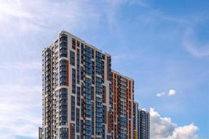 prédio de apartamentos alto recém-construído no fundo do céu azul com nuvens finas de penas foto