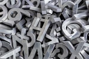 pilha de caracteres do alfabeto de metal prateado cortados por máquina de jato de água foto