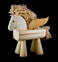 brinquedo de cavalo de madeira com asas em fundo preto foto