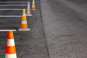 cones de estrada laranja em uma área de condução de asfalto com linhas brancas foto