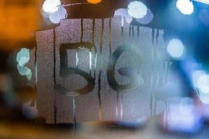 a palavra 5g escrita à mão no vidro da janela molhada à noite com foco seletivo e fundo desfocado bokeh foto