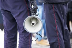 policial segurando megafone de alto-falante ao ar livre, close-up foto