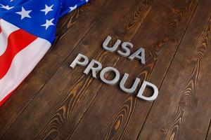 palavras eua orgulhoso colocado com letras de metal prateado na superfície de madeira marrom com bandeira dos estados unidos da américa foto