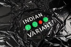 variante indiana de palavras colocada com letras de metal prateado em fundo de saco plástico preto amassado com pequenos modelos de vírus foto