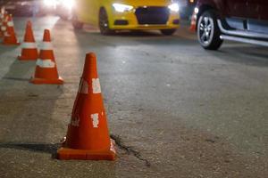linha de cones de trânsito laranja no asfalto da cidade à noite - close-up com foco seletivo foto