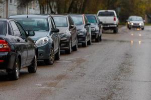 carros estacionados ao lado da estrada suja molhada - telefoto close-up com foco seletivo foto