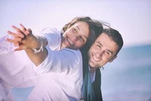 feliz casal jovem se diverte na bela praia foto