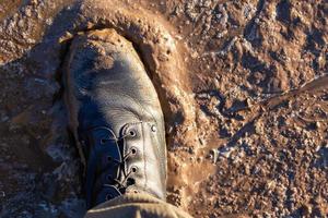 bota do exército em lama molhada closeup vista de cima para baixo com foco seletivo à luz do dia foto