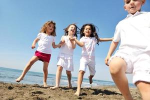 grupo criança feliz jogando na praia foto