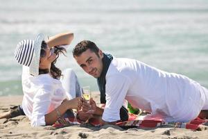 jovem casal desfrutando de piquenique na praia foto