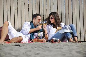 jovem casal desfrutando de piquenique na praia foto