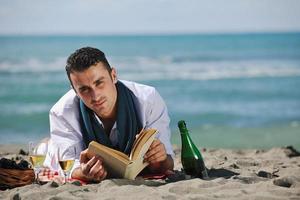 homem lendo livro na praia foto