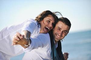 feliz casal jovem se diverte na bela praia foto