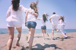 grupo de pessoas felizes se divertir e correr na praia foto