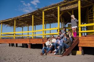 grupo de amigos se divertindo no dia de outono na praia foto