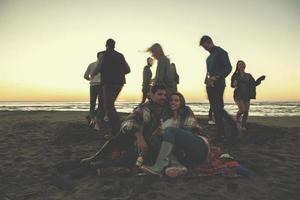 casal curtindo com amigos ao pôr do sol na praia foto