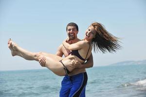 feliz casal jovem se divertir na praia foto