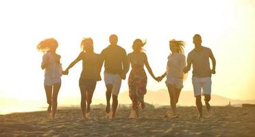 grupo de jovens felizes se divertem na praia foto