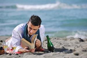 homem lendo livro na praia foto