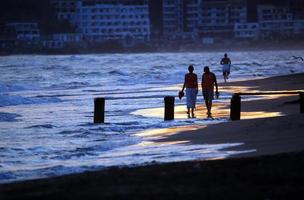 casal romântico caminhando na praia ao pôr do sol foto