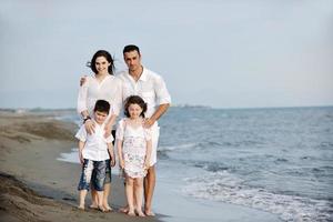 feliz jovem família se divertir na praia foto