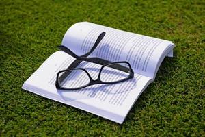 óculos em um livro lá fora com grama foto