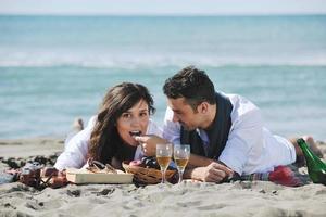 jovem casal desfrutando de piquenique na praia foto