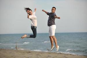 feliz casal jovem se divertir na praia foto