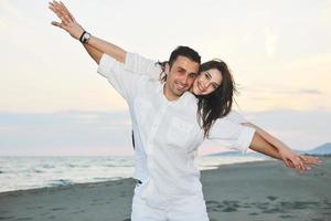 feliz casal jovem se divertir na praia foto