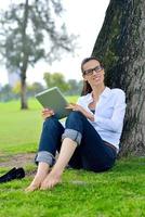 mulher jovem e bonita com tablet no parque foto