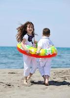 grupo criança feliz jogando na praia foto