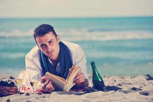 homem lendo livro na praia foto