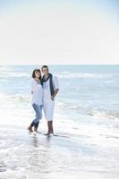 feliz casal jovem se diverte na bela praia foto