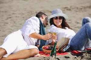 jovem casal desfrutando de piquenique na praia foto