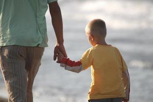 pai e filho caminhando na praia foto