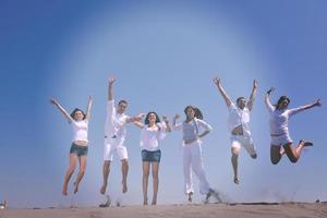 grupo de pessoas felizes se divertir e correr na praia foto