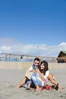 jovem casal desfrutando de piquenique na praia foto