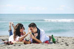 jovem casal desfrutando de piquenique na praia foto