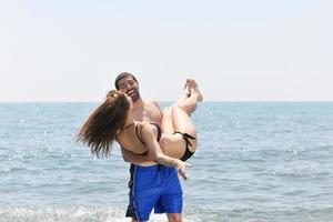 feliz casal jovem se divertir na praia foto