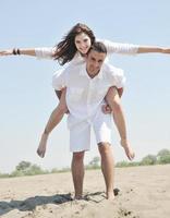 feliz casal jovem se divertir na praia foto