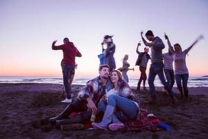 casal curtindo com amigos ao pôr do sol na praia foto