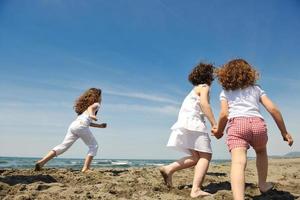 grupo criança feliz jogando na praia foto