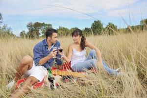 casal feliz desfrutando de piquenique no campo em grama longa foto