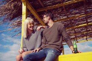 jovem casal bebendo cerveja juntos na praia foto