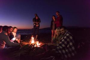 casal curtindo com amigos ao pôr do sol na praia foto